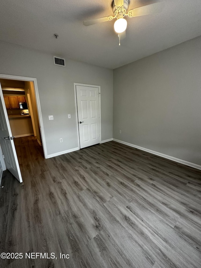 unfurnished bedroom featuring ceiling fan, dark wood-type flooring, and a textured ceiling