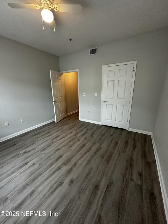 unfurnished bedroom with a closet, dark hardwood / wood-style floors, and ceiling fan