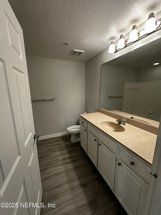 bathroom with wood-type flooring, toilet, a textured ceiling, and vanity