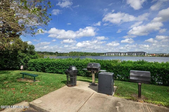 view of home's community with a lawn, a water view, and a patio