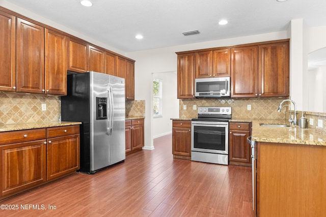 kitchen featuring sink, backsplash, dark hardwood / wood-style flooring, light stone counters, and stainless steel appliances