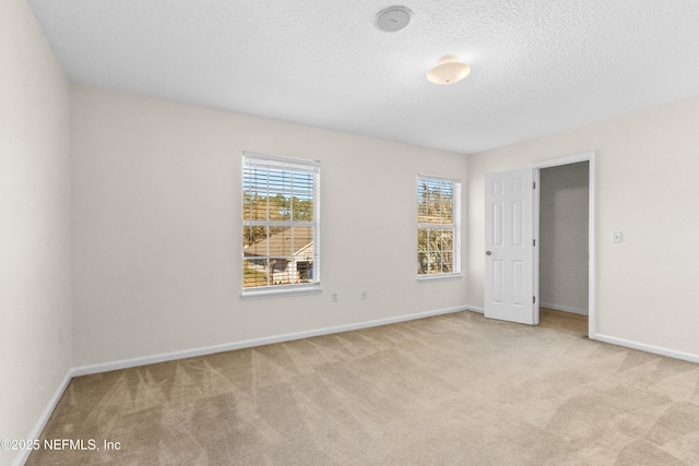 unfurnished room featuring light colored carpet and a textured ceiling