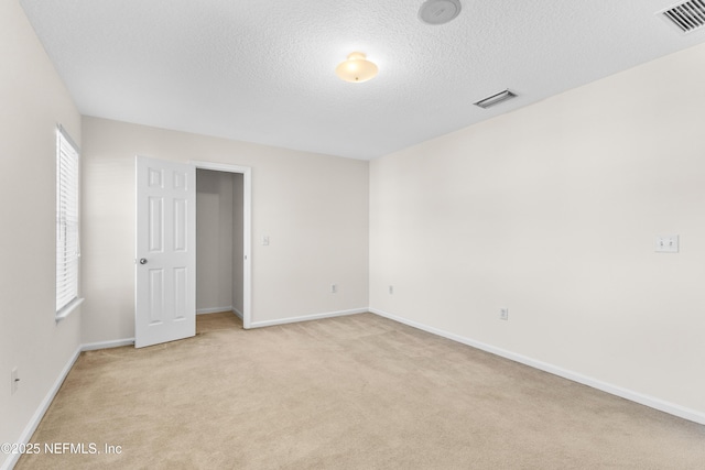 unfurnished room with light colored carpet and a textured ceiling