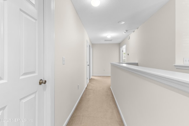 hall featuring light colored carpet and a textured ceiling