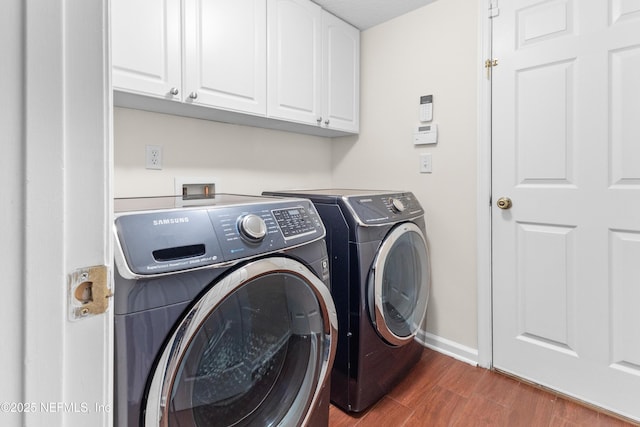 clothes washing area featuring cabinets, dark hardwood / wood-style floors, and washer and clothes dryer