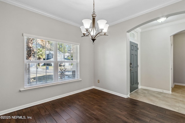 empty room with hardwood / wood-style flooring, ornamental molding, and a notable chandelier