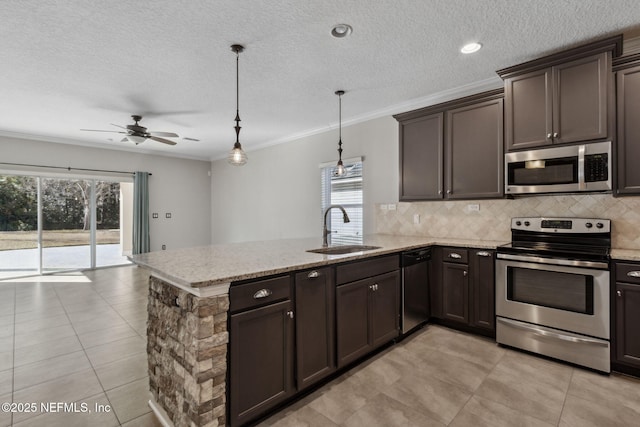 kitchen featuring pendant lighting, sink, appliances with stainless steel finishes, ornamental molding, and kitchen peninsula