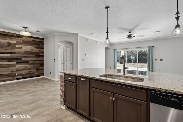 kitchen with sink, wooden walls, light stone countertops, and dishwasher