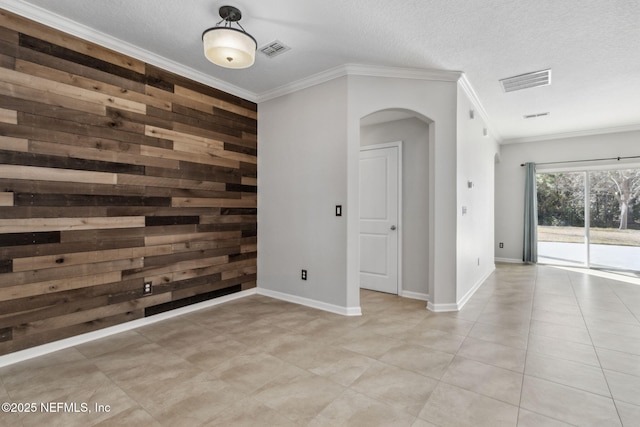 empty room featuring ornamental molding, wooden walls, and a textured ceiling