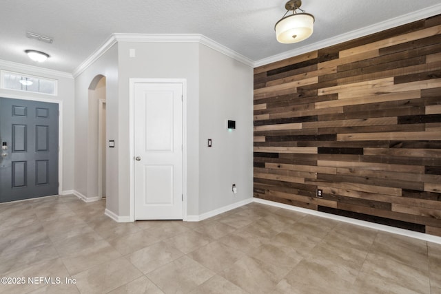 entryway featuring ornamental molding, wooden walls, and a textured ceiling