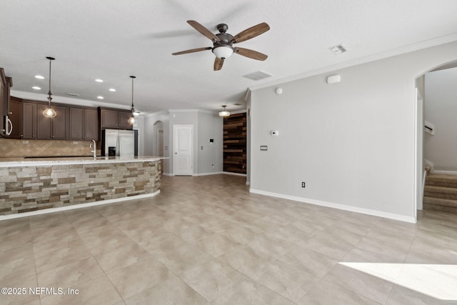 unfurnished living room featuring ceiling fan, ornamental molding, sink, and a textured ceiling