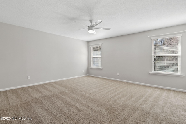 spare room with ceiling fan, plenty of natural light, carpet, and a textured ceiling