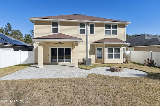 rear view of property featuring a fire pit, a lawn, ceiling fan, a patio, and central AC unit