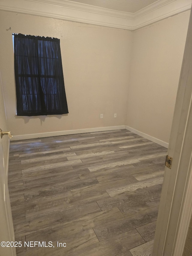 empty room with wood-type flooring and crown molding