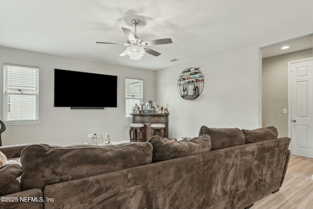 living room with light wood-style floors, visible vents, and a ceiling fan