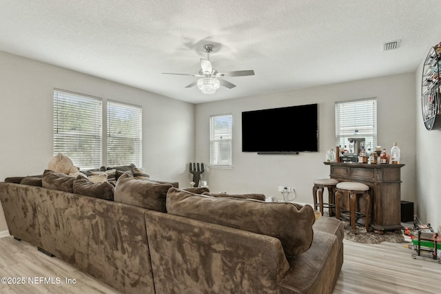 living room with visible vents, ceiling fan, a textured ceiling, and light wood finished floors