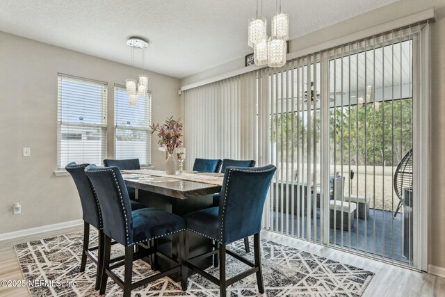 dining area with a chandelier, a textured ceiling, baseboards, and wood finished floors