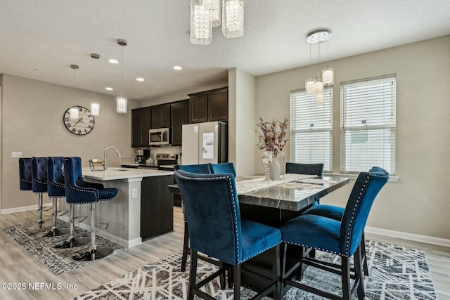 dining room with light wood-style flooring, baseboards, a textured ceiling, and recessed lighting