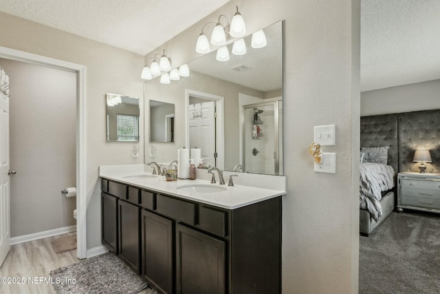 ensuite bathroom with a stall shower, a sink, visible vents, and connected bathroom