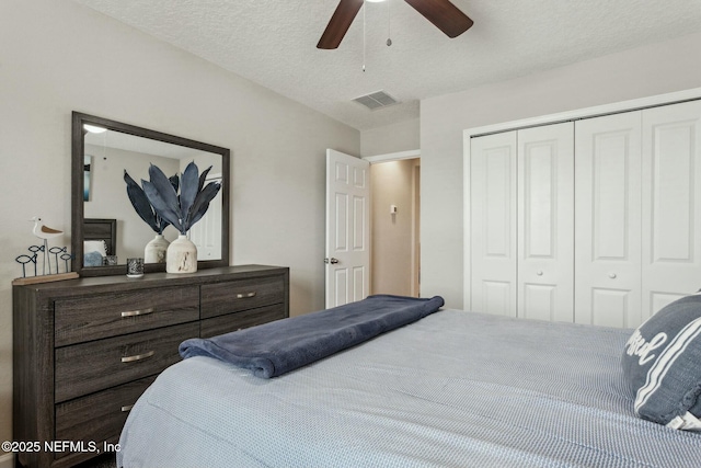 bedroom with ceiling fan, a textured ceiling, visible vents, and a closet