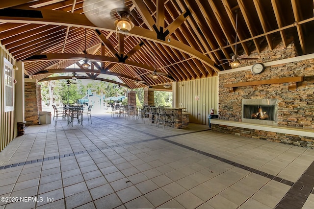 view of patio featuring outdoor dining space, an outdoor stone fireplace, ceiling fan, and a gazebo