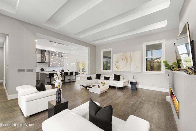 living room featuring a tray ceiling and dark wood-type flooring