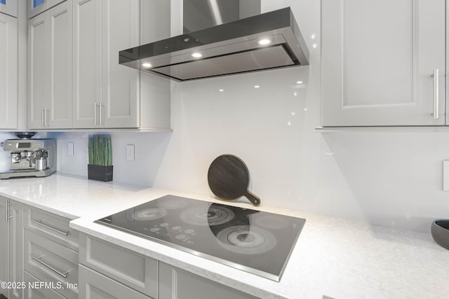 kitchen with black electric cooktop, light stone counters, and wall chimney exhaust hood