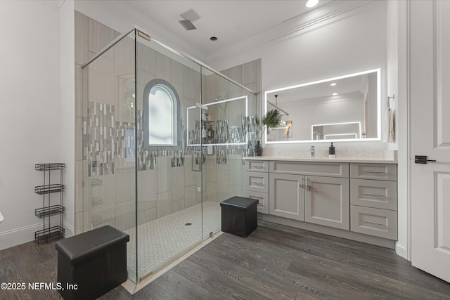 bathroom featuring crown molding, hardwood / wood-style floors, vanity, and walk in shower