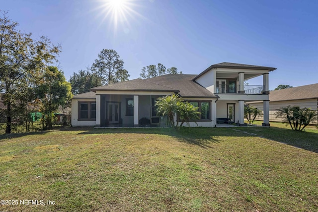 view of front of house with a sunroom, a front yard, and a balcony