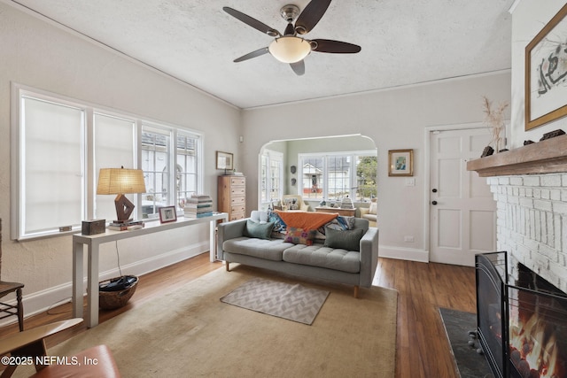 living room with ceiling fan, hardwood / wood-style floors, a textured ceiling, and a fireplace