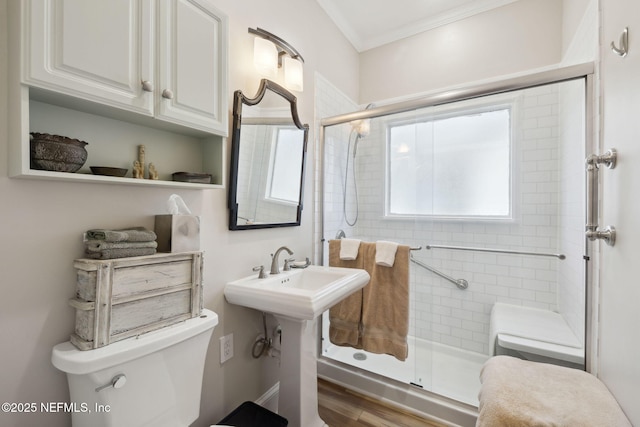 bathroom with an enclosed shower, hardwood / wood-style flooring, ornamental molding, and toilet