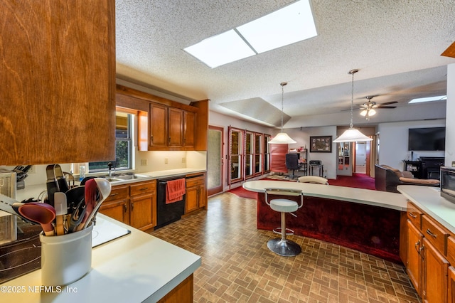 kitchen featuring sink, black dishwasher, pendant lighting, and a textured ceiling