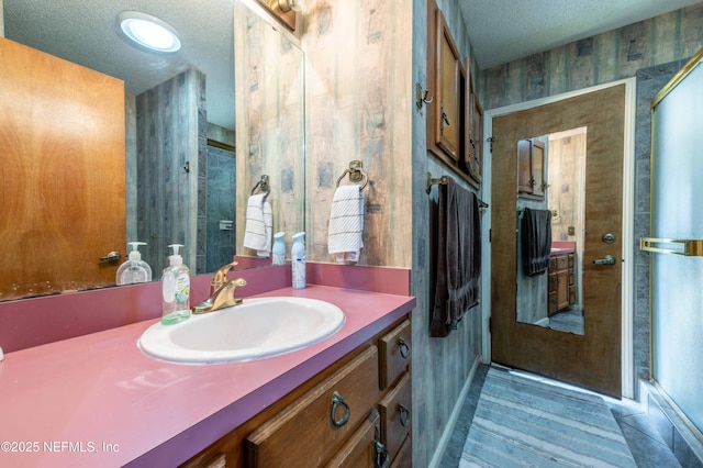 bathroom with vanity, a shower with door, and a textured ceiling