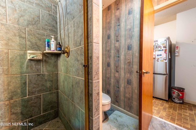 bathroom with a tile shower and toilet