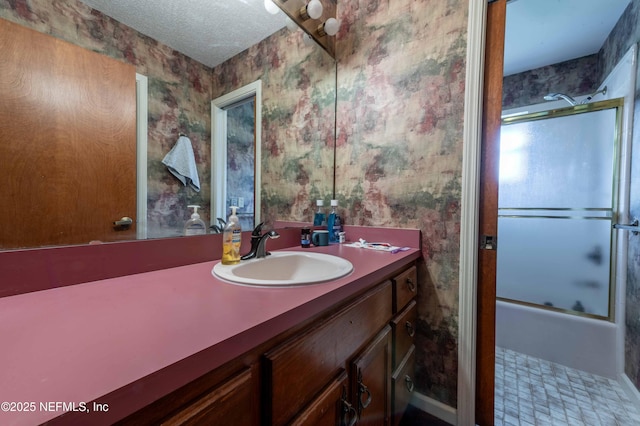 bathroom featuring vanity, bath / shower combo with glass door, and a textured ceiling