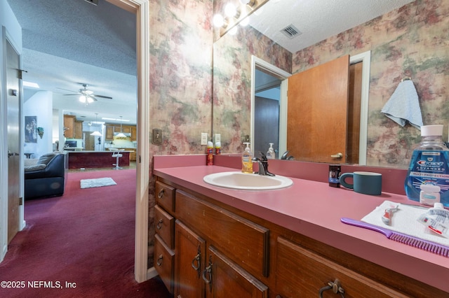 bathroom with vanity, ceiling fan, and a textured ceiling