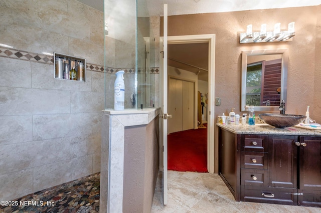 bathroom featuring tiled shower and vanity