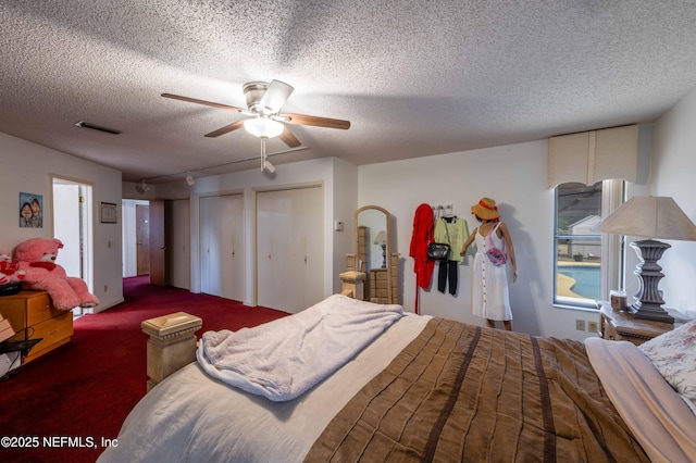 carpeted bedroom featuring multiple closets, ceiling fan, and a textured ceiling