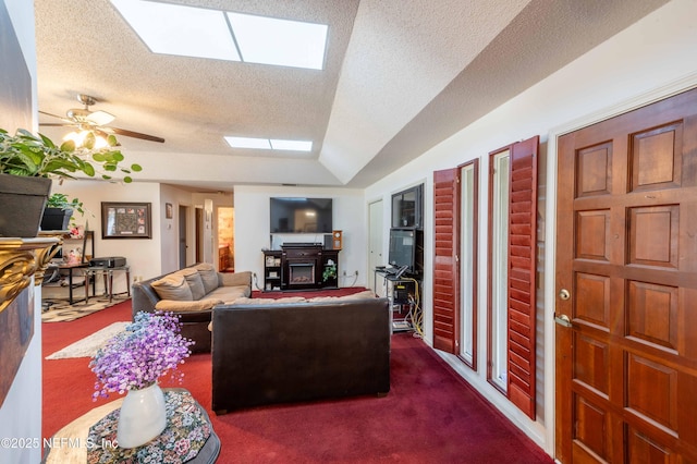 living room featuring dark colored carpet, vaulted ceiling with skylight, ceiling fan, and a textured ceiling