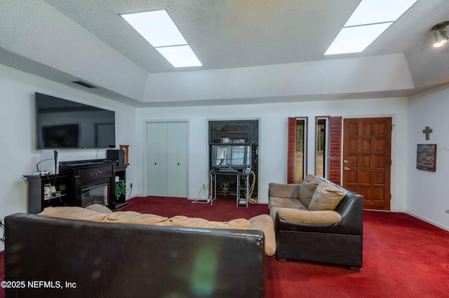 living room with carpet floors, a textured ceiling, a fireplace, and a tray ceiling