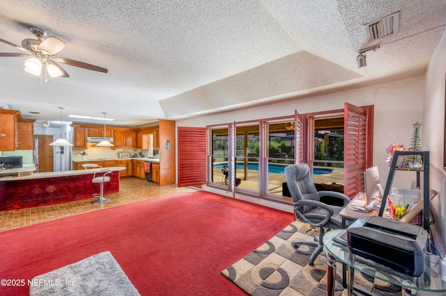 carpeted office space with a raised ceiling, a textured ceiling, and ceiling fan