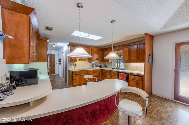 kitchen featuring pendant lighting, sink, black appliances, a textured ceiling, and kitchen peninsula