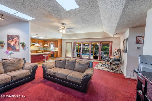 living room featuring lofted ceiling with skylight, ceiling fan, and carpet