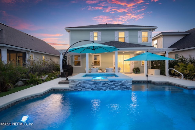 back house at dusk featuring a pool with hot tub and a patio