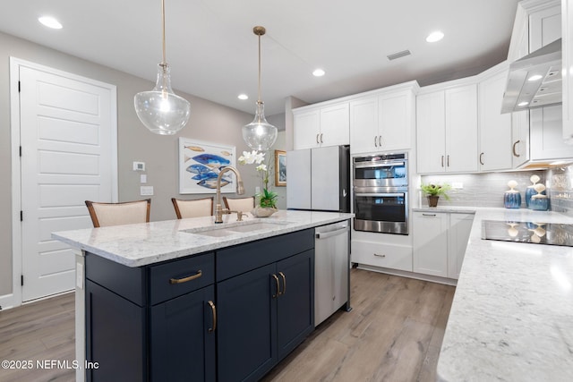 kitchen with an island with sink, appliances with stainless steel finishes, sink, and white cabinets