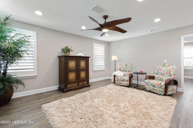 sitting room with dark wood-type flooring and ceiling fan