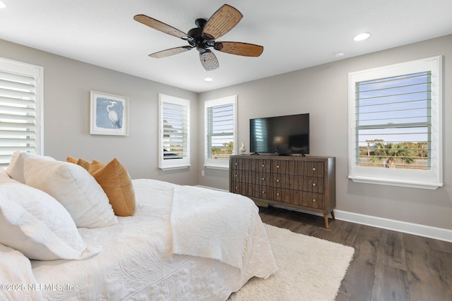 bedroom with ceiling fan, dark hardwood / wood-style flooring, and multiple windows