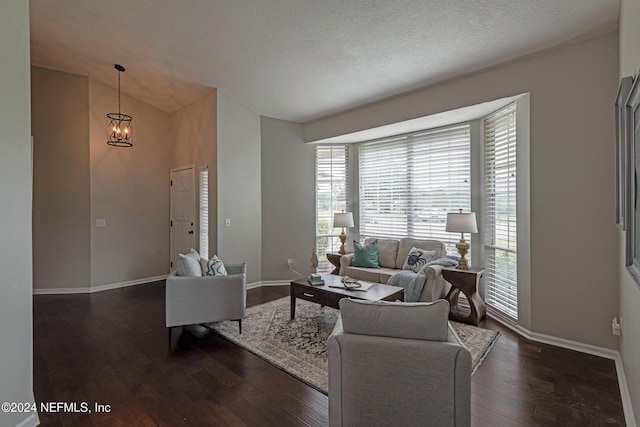 living room featuring dark hardwood / wood-style flooring, a textured ceiling, and a notable chandelier