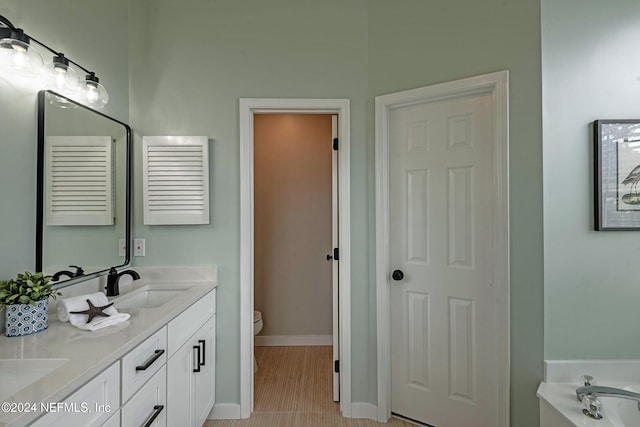 bathroom with vanity, a washtub, and toilet