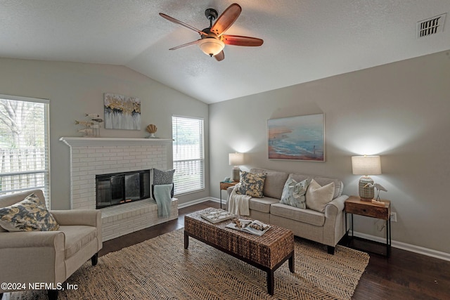 living room featuring vaulted ceiling, a textured ceiling, dark hardwood / wood-style floors, ceiling fan, and a fireplace